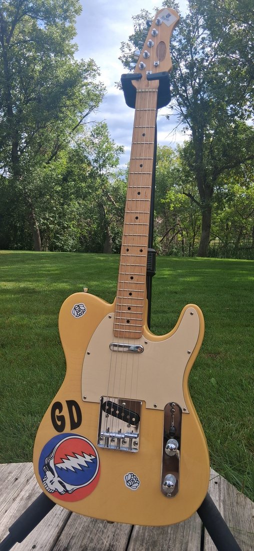 Yellow Tele-style electric guitar photographed outdoors on a stand.
